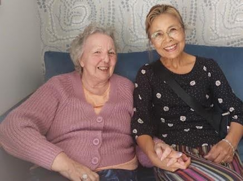 two women sat down together holding hands