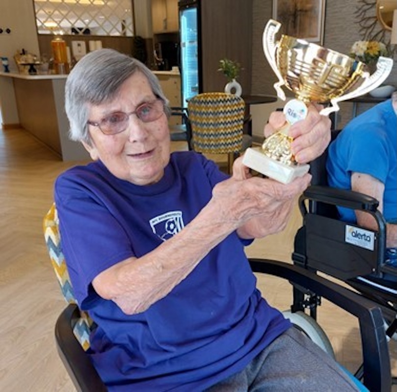 one of our residents sat holding her sports day trophy smiling