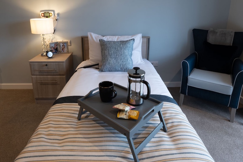 one of our bedrooms with the bed made up, an armchair and bedside table