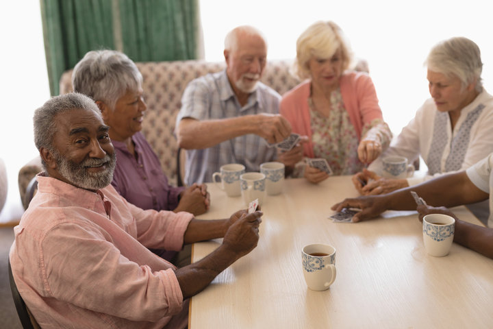 Group of senior people playing cards in living room