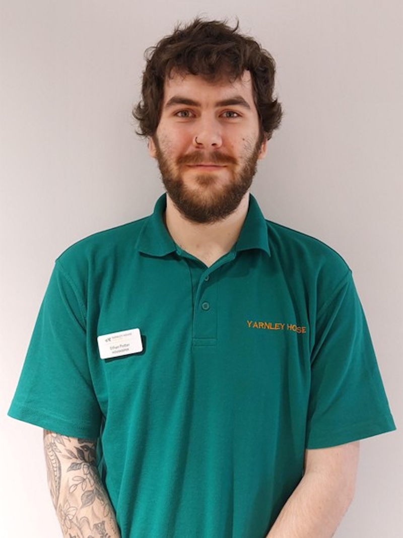 man with brown hair wearing a green housekeeper polo smiling having his photo taken for the team page