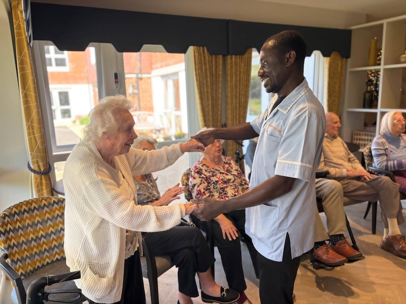 resident and carer smiling at each other and holding hands