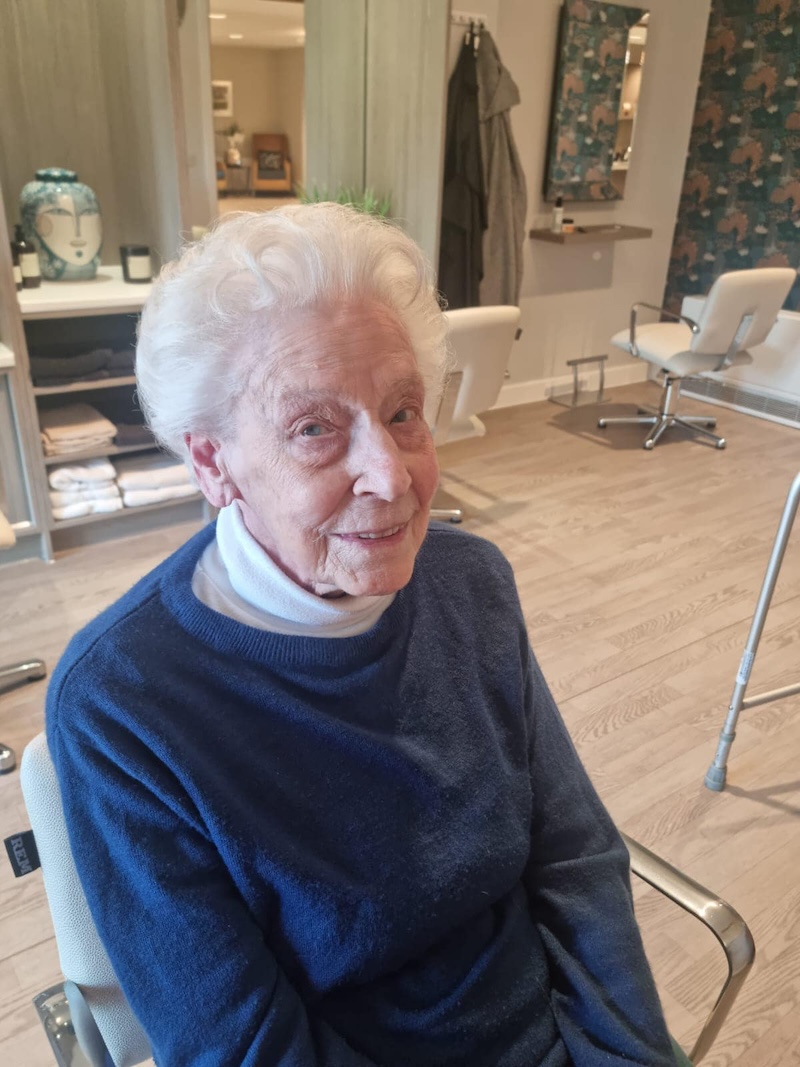 resident sat in the hair salon smiling after having her hair done