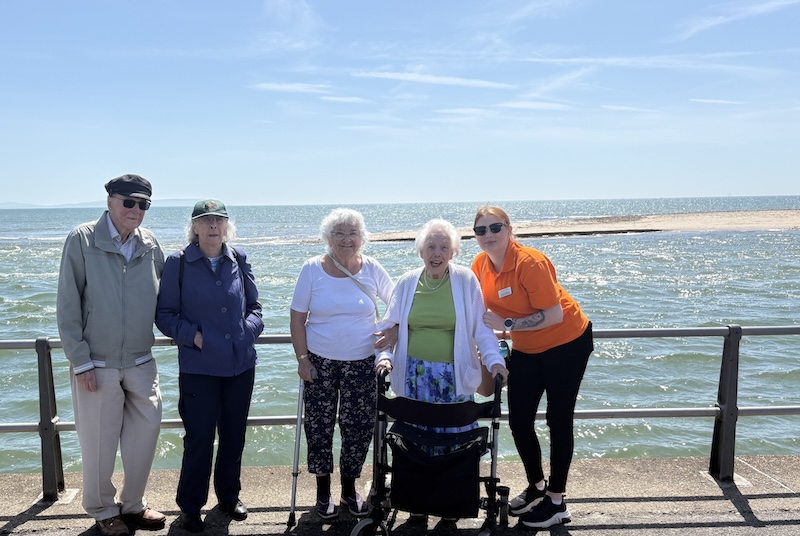 a group of residents stood at the beach together smiling
