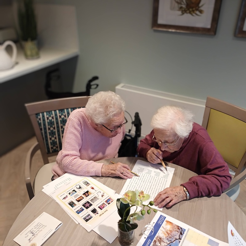 2 female residents sat down doing a word search together