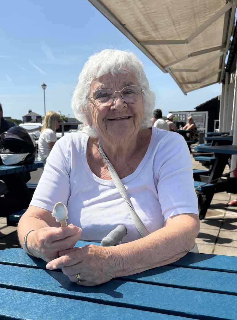 one of our female residents sat on a blue bench smiling